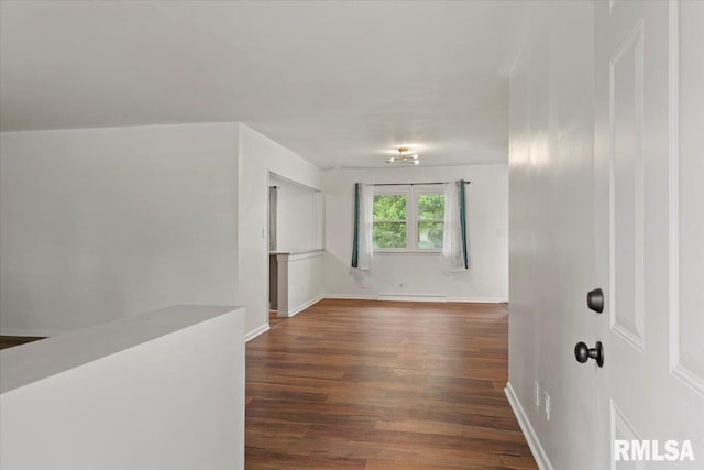 spare room featuring dark wood-type flooring, a baseboard radiator, and baseboards