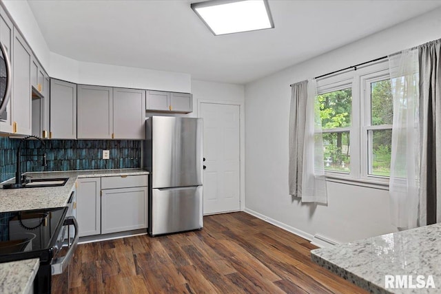kitchen with freestanding refrigerator, electric range, baseboards, tasteful backsplash, and gray cabinetry