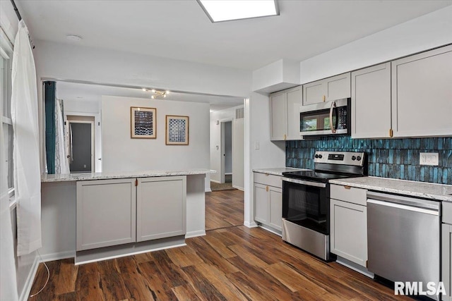 kitchen with decorative backsplash, a peninsula, dark wood-style floors, gray cabinets, and appliances with stainless steel finishes