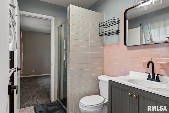 bathroom with vanity, a shower stall, toilet, and tile walls
