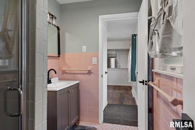 bathroom featuring vanity, wainscoting, tile walls, tile patterned floors, and a stall shower
