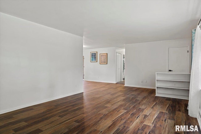 spare room with baseboards and dark wood-style floors
