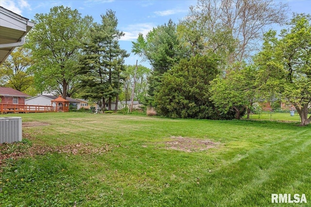 view of yard with central AC and fence