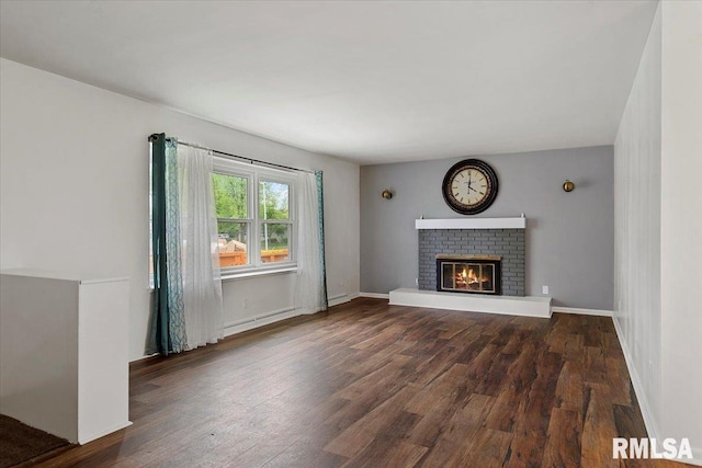 unfurnished living room with baseboards, wood finished floors, and a fireplace