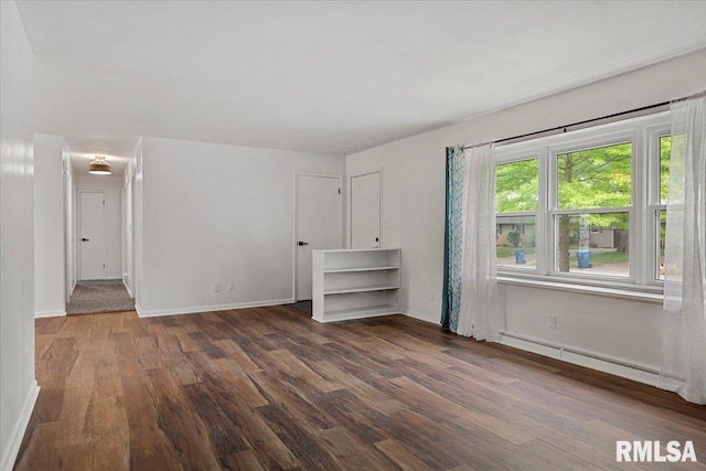 empty room with baseboards, wood finished floors, and a baseboard radiator