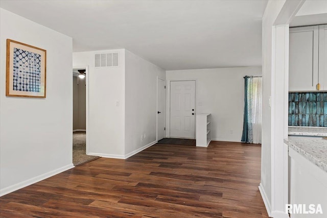 interior space with baseboards, visible vents, and dark wood finished floors