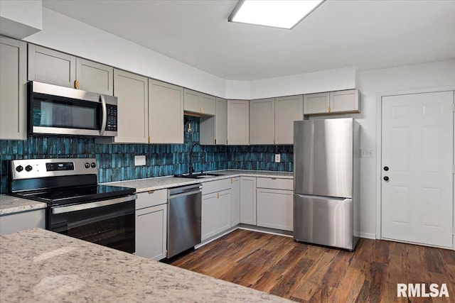 kitchen featuring gray cabinets, appliances with stainless steel finishes, a sink, and tasteful backsplash