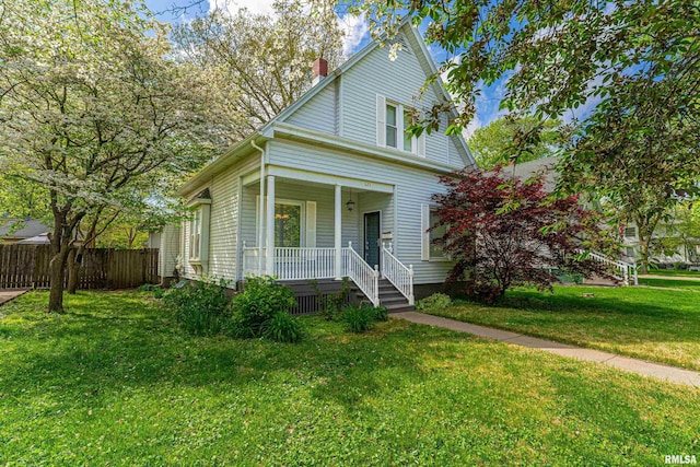view of front of house featuring fence, a chimney, a porch, and a front yard
