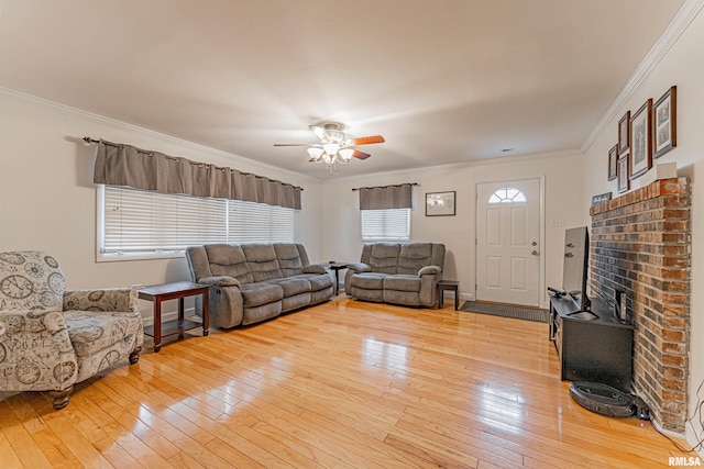 living room with a ceiling fan, ornamental molding, light wood-style flooring, and a wood stove