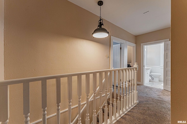 corridor with carpet floors and a textured wall