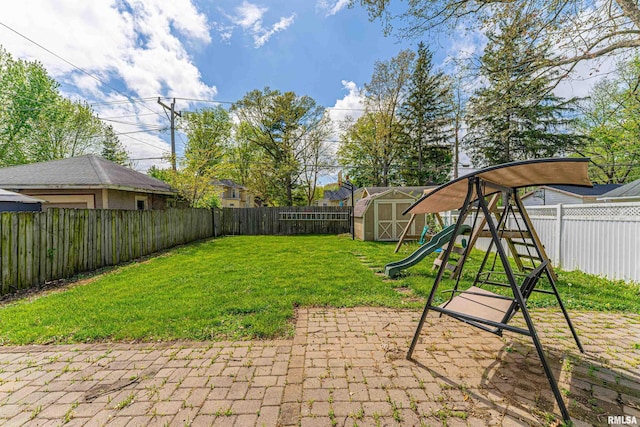 view of yard with a storage shed, an outbuilding, a fenced backyard, a playground, and a patio