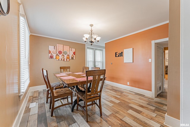 dining area with light wood-style floors, baseboards, an inviting chandelier, and ornamental molding