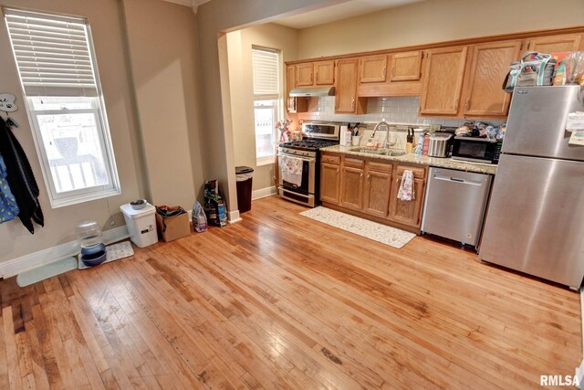 629 W Adams St, Taylorville, IL 62568 - kitchen featuring appliances with stainless steel finishes, a sink, under cabinet range hood, light wood-style flooring, and tasteful backsplash