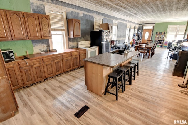 629 W Adams St, Taylorville, IL 62568 - kitchen featuring freestanding refrigerator, white electric range, a sink, light wood finished floors, and a kitchen bar