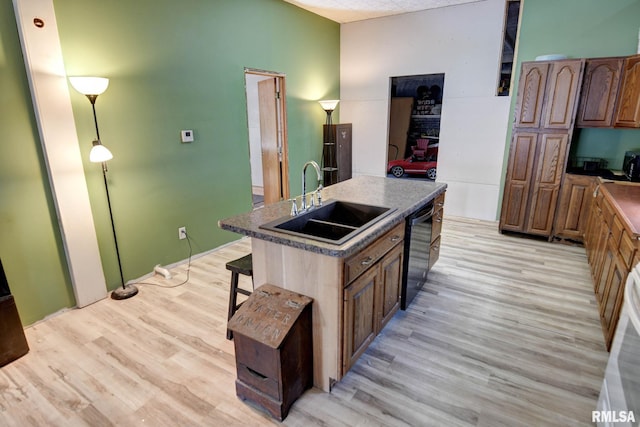 629 W Adams St, Taylorville, IL 62568 - kitchen featuring a sink, dishwasher, light wood finished floors, a center island with sink, and a breakfast bar