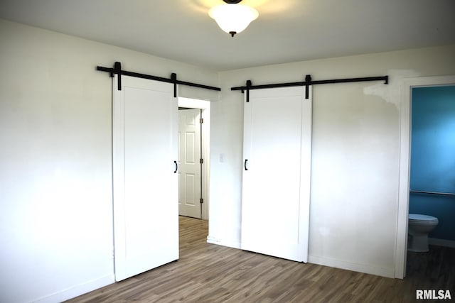 24 Parkway Dr, Sherman, IL 62684 - unfurnished bedroom featuring a barn door, wood finished floors, and baseboards