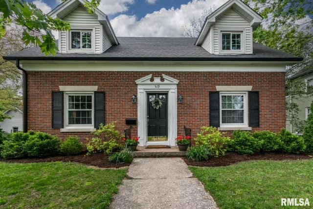 cape cod house featuring brick siding and a front lawn