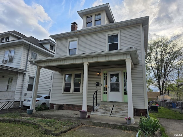 american foursquare style home with covered porch, fence, and a chimney