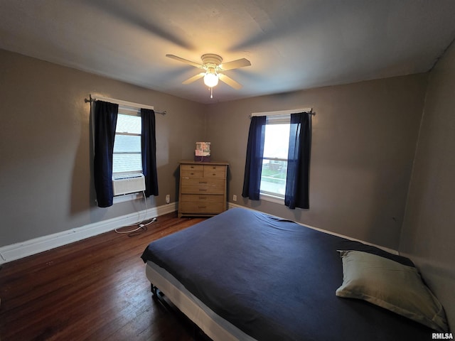 bedroom featuring ceiling fan, baseboards, multiple windows, and wood finished floors