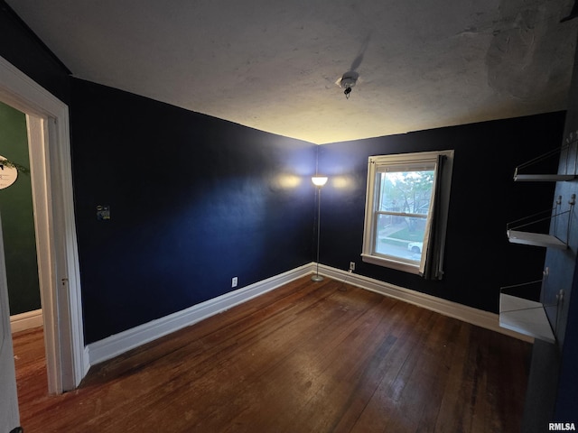 unfurnished room featuring baseboards and hardwood / wood-style flooring