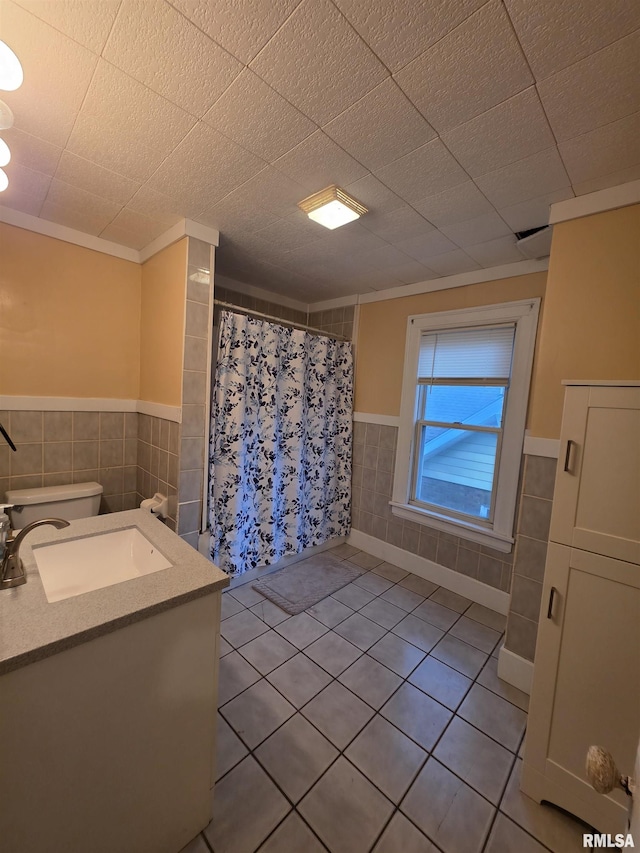 full bath featuring crown molding, vanity, tile patterned floors, a wainscoted wall, and curtained shower