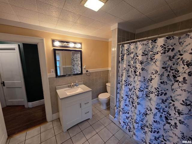 bathroom with tile patterned flooring, vanity, toilet, and tile walls