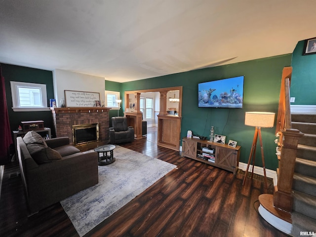 living room featuring baseboards, wood finished floors, stairway, and a fireplace