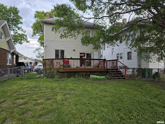 rear view of house with a lawn, a deck, a chimney, and a fenced backyard