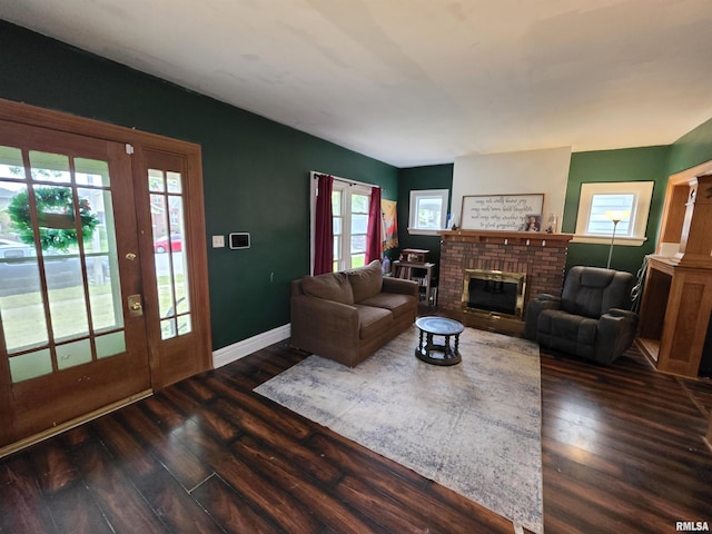 living room with baseboards, a brick fireplace, and dark wood-style flooring