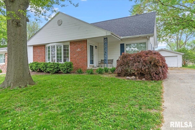 view of front of property with brick siding, a shingled roof, an outdoor structure, and a front lawn