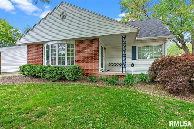 view of front of property featuring a porch, brick siding, and a front yard