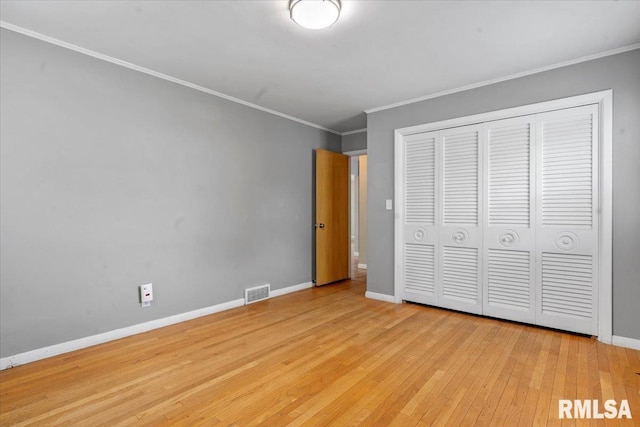unfurnished bedroom with baseboards, ornamental molding, hardwood / wood-style floors, and visible vents