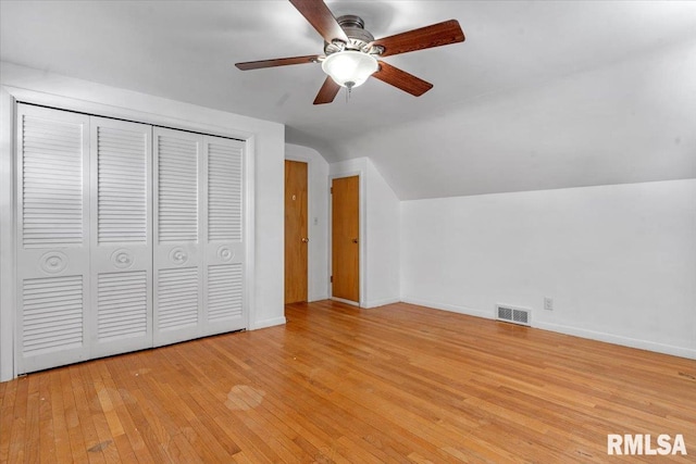 unfurnished bedroom featuring baseboards, wood-type flooring, vaulted ceiling, and visible vents