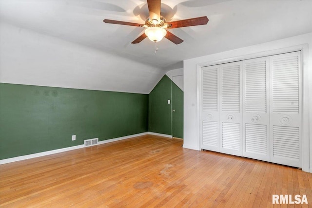 additional living space with visible vents, lofted ceiling, baseboards, light wood-style floors, and ceiling fan