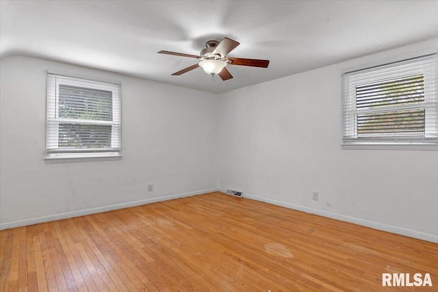 empty room with light wood-style floors, baseboards, a ceiling fan, and visible vents