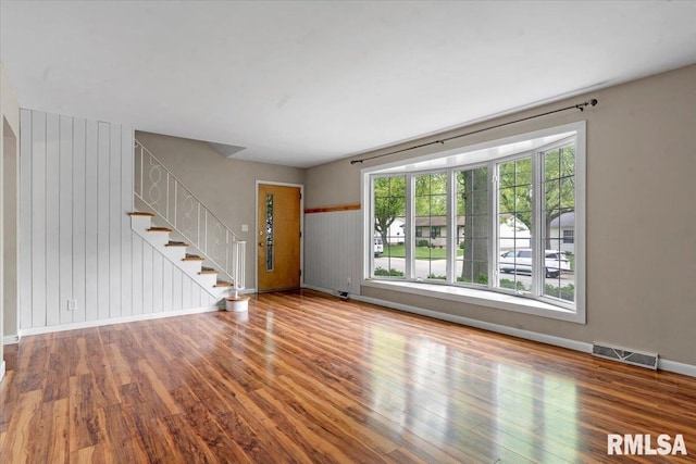 unfurnished living room with visible vents, baseboards, stairs, and wood finished floors