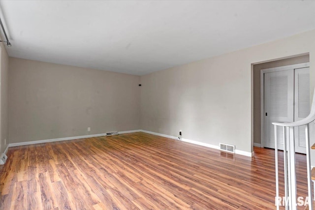 spare room featuring visible vents, baseboards, and wood finished floors