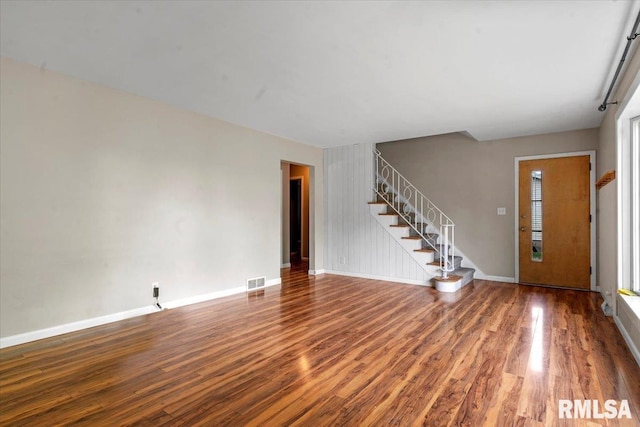 unfurnished living room with baseboards, stairs, wood finished floors, and visible vents