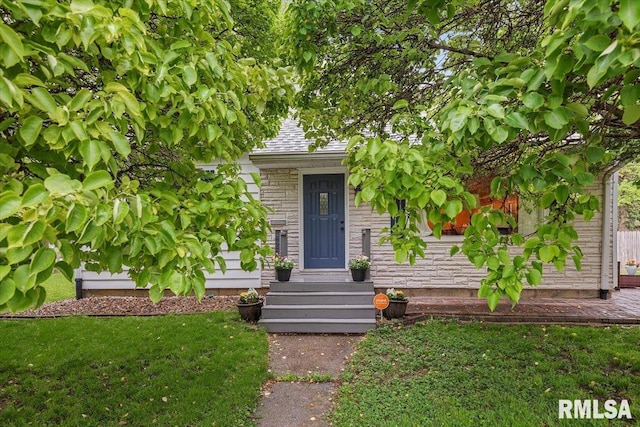 doorway to property with a shingled roof and a yard