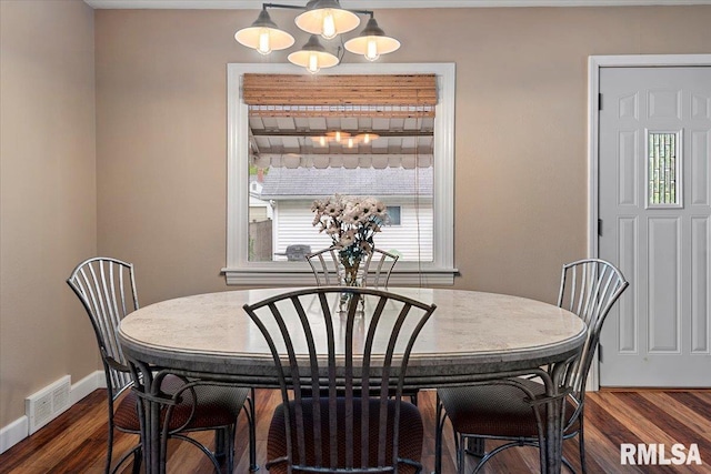 dining area with a chandelier, baseboards, visible vents, and dark wood-type flooring