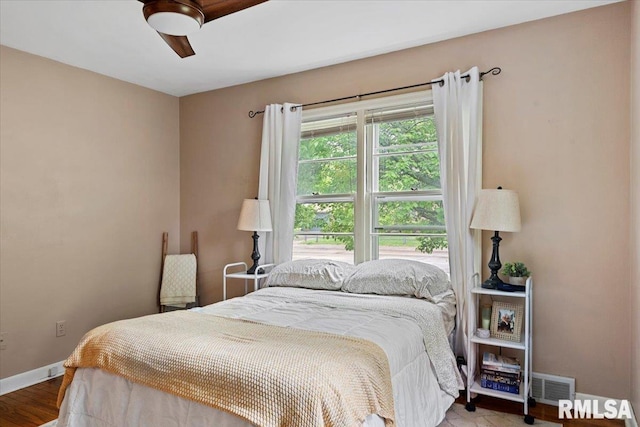 bedroom featuring baseboards, visible vents, ceiling fan, and wood finished floors