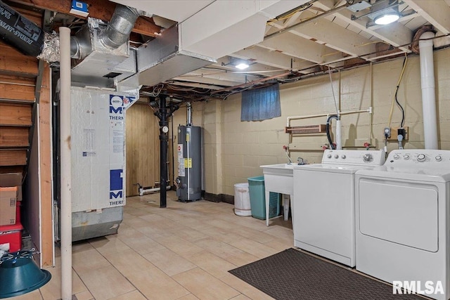 clothes washing area with separate washer and dryer, laundry area, and water heater