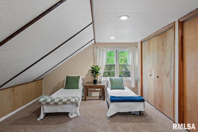 living area featuring baseboards, wooden walls, a textured ceiling, carpet flooring, and vaulted ceiling