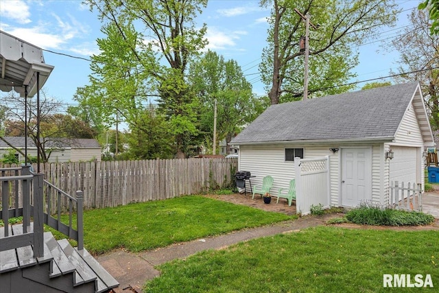 view of yard with a detached garage, fence, and an outbuilding