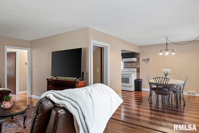 bedroom with visible vents, dark wood finished floors, baseboards, and a chandelier
