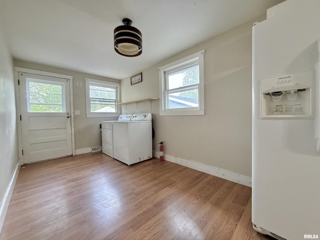 washroom with baseboards, laundry area, light wood finished floors, and washing machine and clothes dryer
