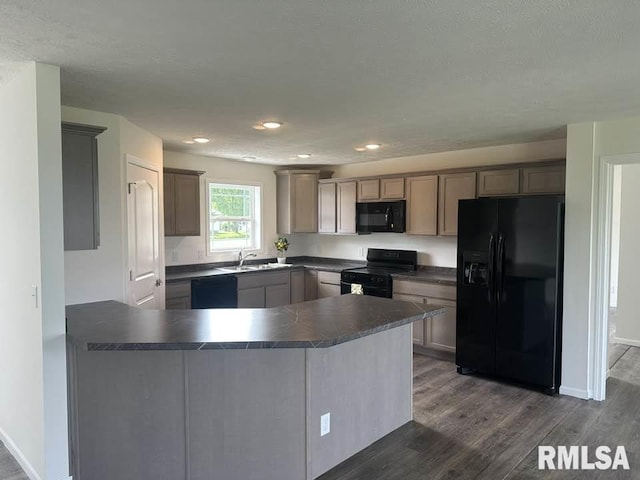 kitchen featuring dark countertops, a sink, a peninsula, dark wood-style floors, and black appliances