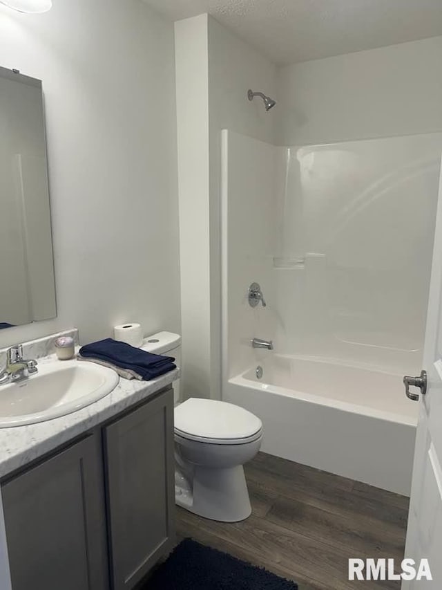 full bath featuring toilet, washtub / shower combination, wood finished floors, and vanity
