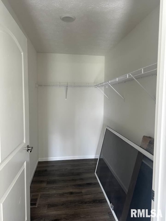 walk in closet featuring dark wood-style flooring and visible vents
