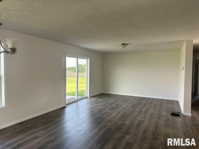 empty room featuring a textured ceiling, baseboards, and dark wood finished floors